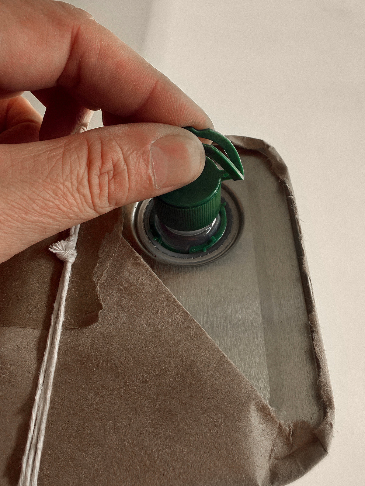 Hand adjusting a green valve on a beige fabric bag.